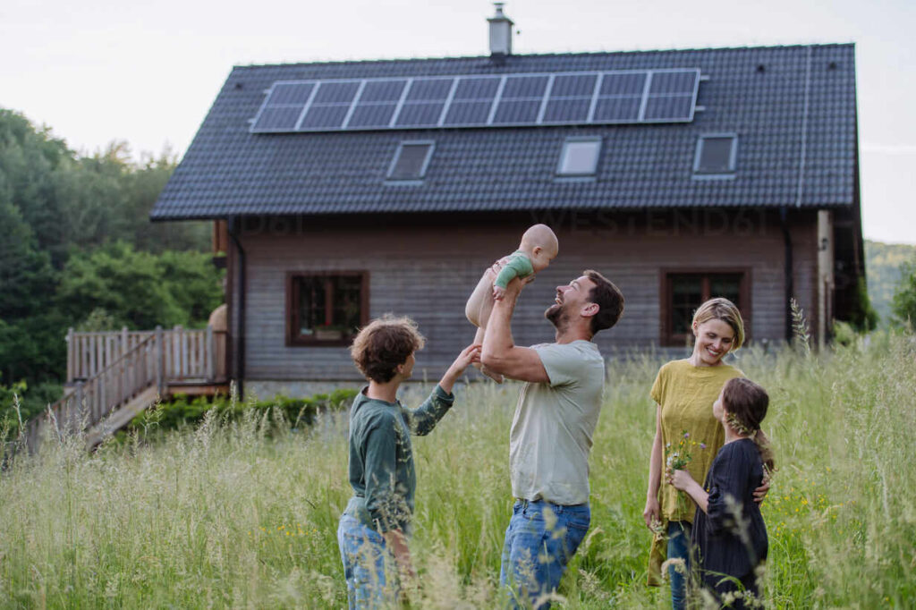 Happy family near their house with a solar panels. Alternative energy, saving resources and sustainable lifestyle concept. Famiglia con casa a energia solare grazie al Conto Termico 3.0
